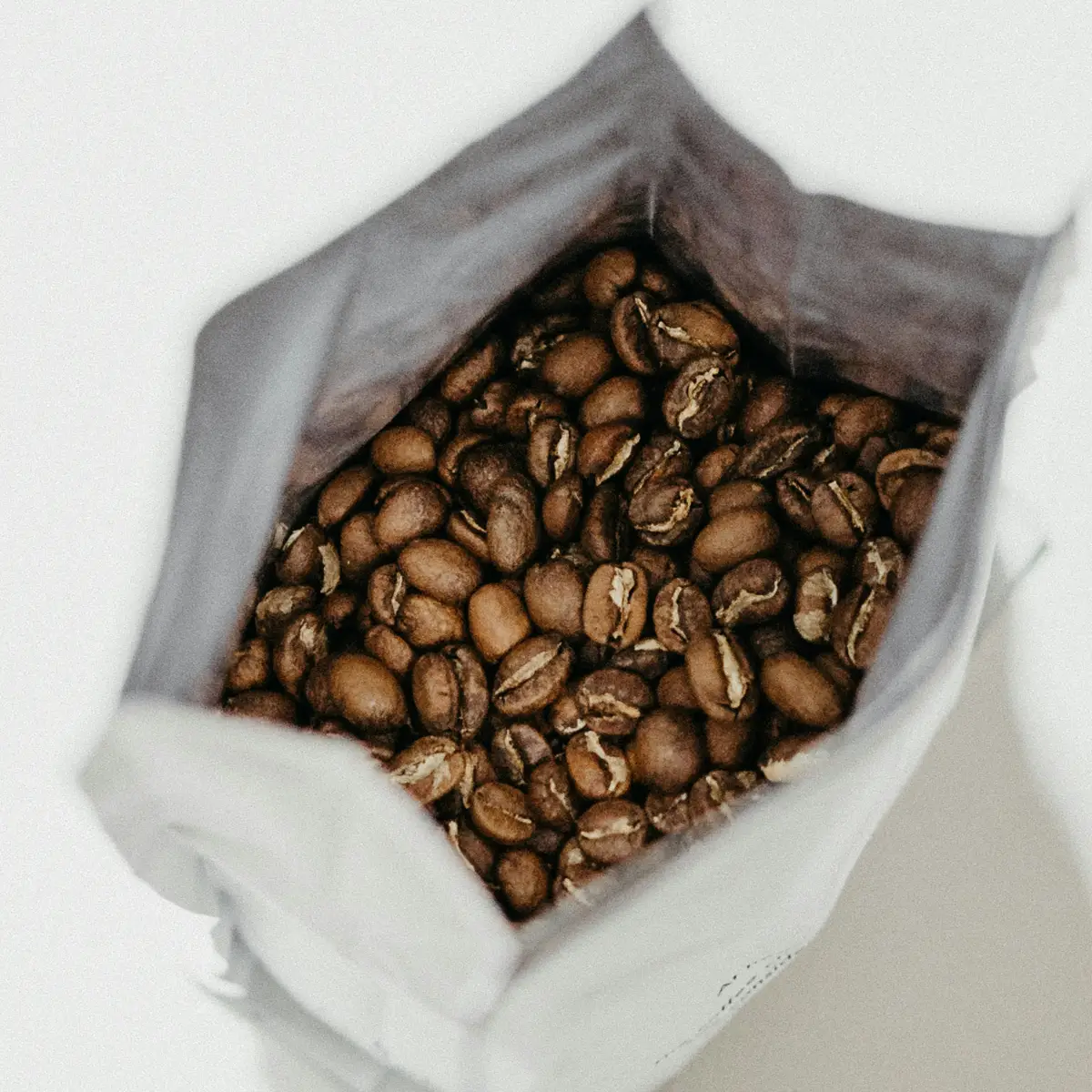 looking down at a cup of hot coffee surrounded by coffee beans