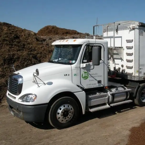 white semi-truck with green Sustainable Resources Group logo on door, surrounded by piles of dirt